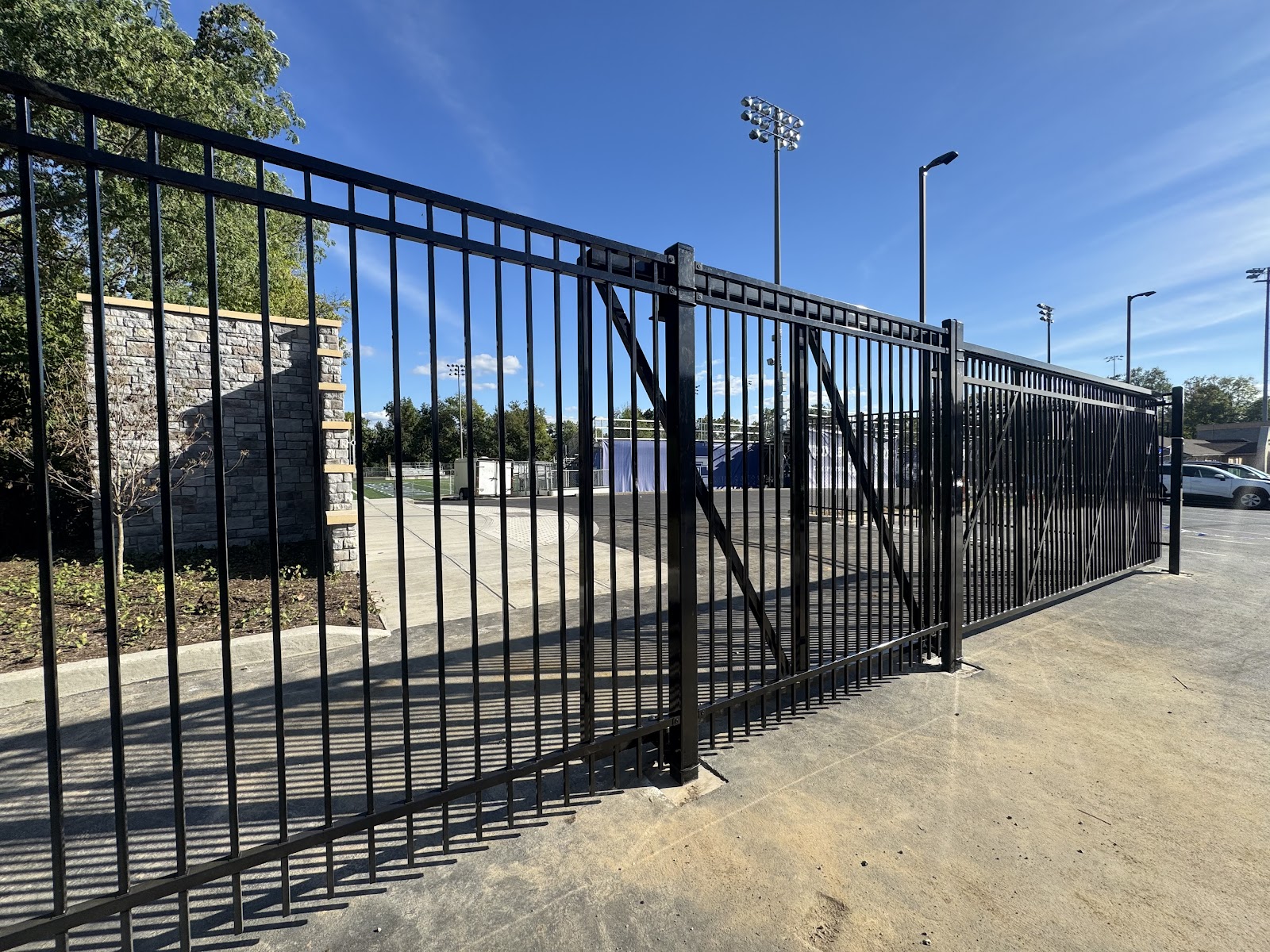 Black ornamental sliding gate securing a paved property entrance
